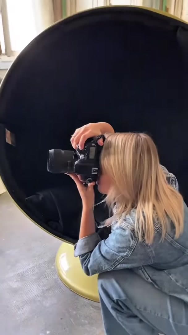 Фотограф работает с камерой и большим отражателем